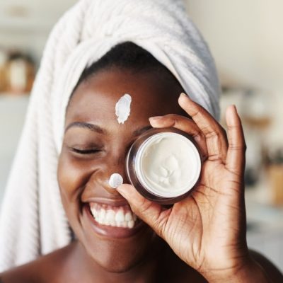 Shot of a beautiful young woman holding up a face cream product